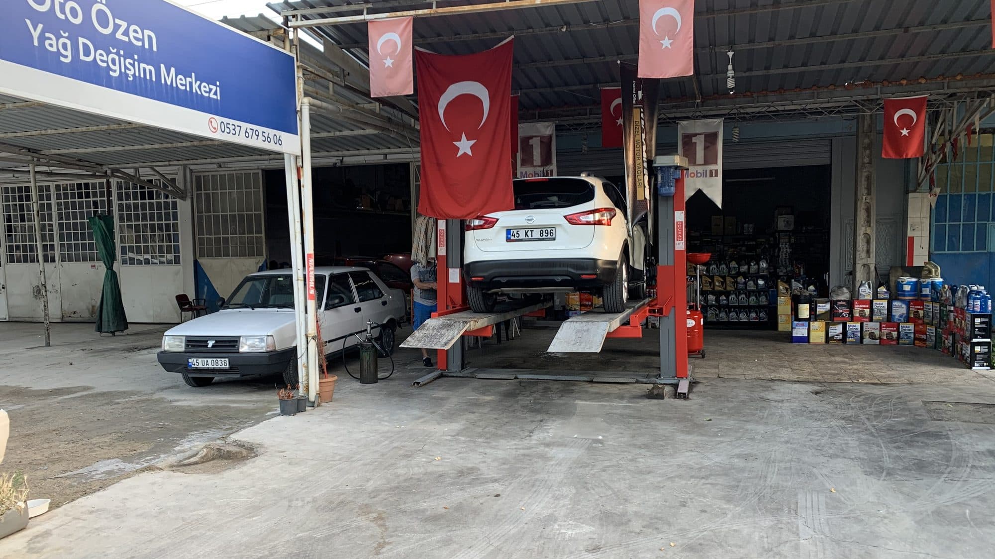 Oto Özen Yağ Değişim Merkezi'nin Manisa Küçük Sanayi'deki dükkânı; liftte beyaz bir SUV ve raflarda motor yağları